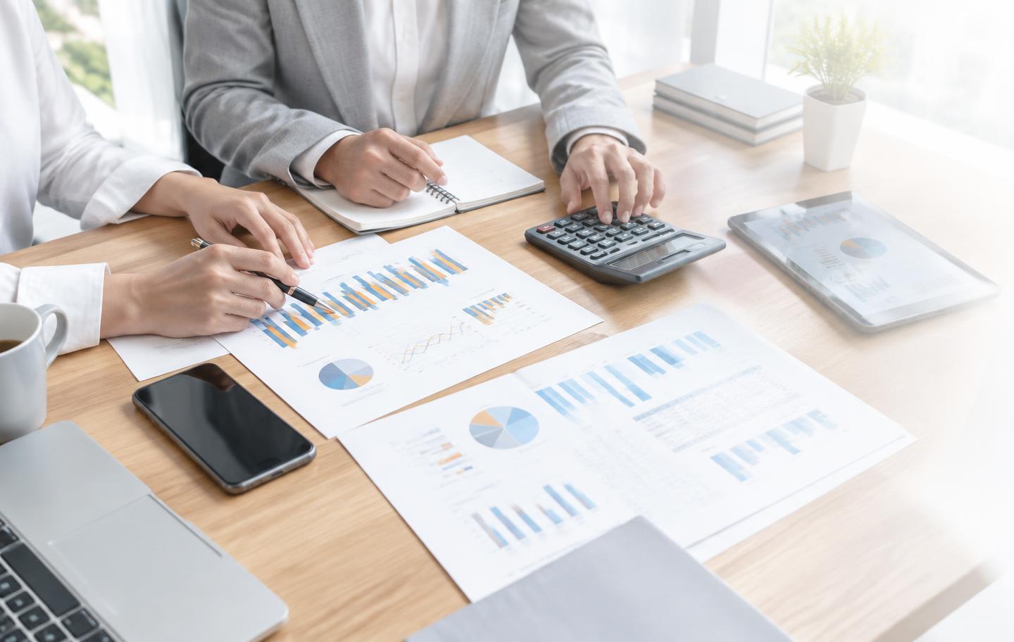 Mesa de trabalho com gráficos, calculadora e relatórios financeiros